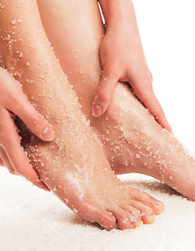 Hands exfoliating feet with chemical exfoliation.